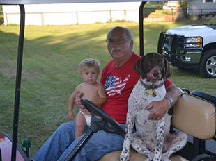 man with child and dog in golf cart