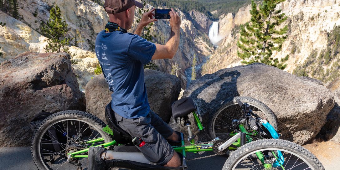 Visitor photographing Lower Falls from an off-road wheelchair at Artist Point in Yellowstone
