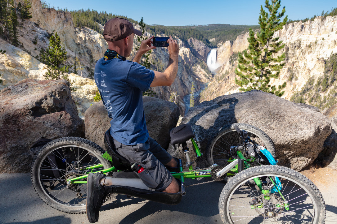 Visitor photographing Lower Falls from an off-road wheelchair at Artist Point in Yellowstone