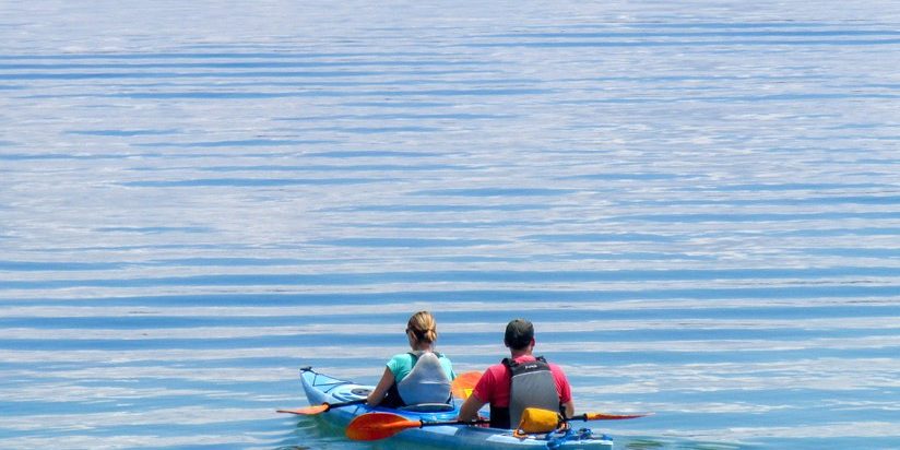 Kayakers on Yellowstone Lake Two visitors resting their paddles in a tandem kayak on Yellowstone Lake